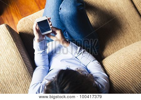 Aerial View Of Girl Reading A Phone While Sitting In A Couch.
