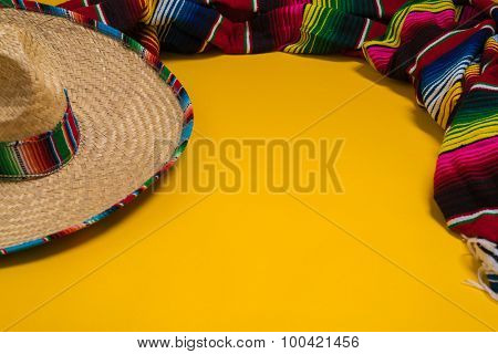 A traditional Mexican Sombrero and serape blanket on a yellow background with copy space