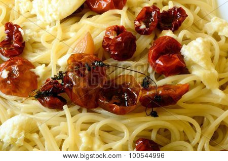 Spaghetti with mozzarella, dried tomatoes and basil on red background.