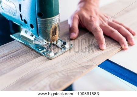 DIY worker cutting wooden panel with jig saw