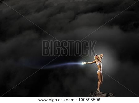 Hot young dancing woman in white bikini on dark background