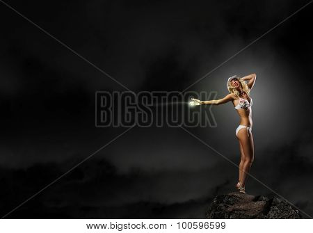 Hot young dancing woman in white bikini on dark background