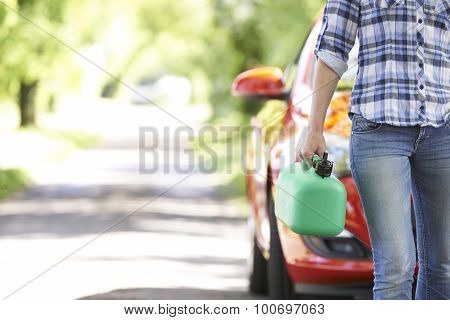 Female Motorist Carrying Fuel Can Next To Broken Down Car