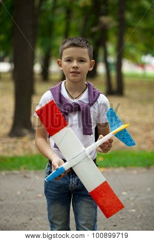 Portrait of a little Boy holds airframe in autumn park