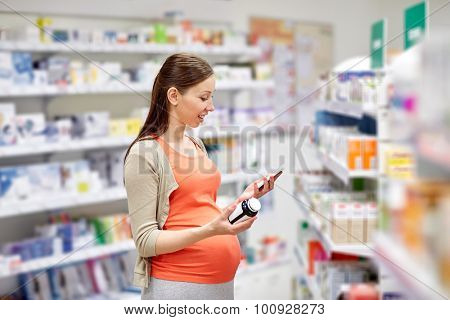 pregnancy, medicine, pharmaceutics, health care and people concept - happy pregnant woman with smartphone choosing medication at pharmacy