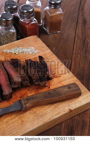 fresh roast red beef meat fillet mignon cutted on wooden plate with vintage fork many different kinds of dry spice over table