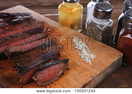 fresh roast red beef meat fillet mignon cutted on wooden plate with vintage fork many different kinds of dry spice over table