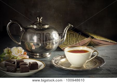 Tea In A Porcelain Cup, Old Fashioned Silver Teapot, Chocolate Cookies And A Good Book On Rustic Woo