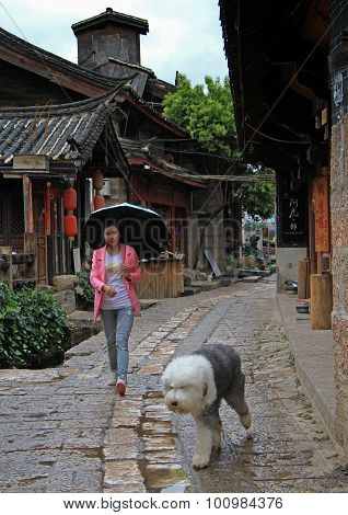 woman is walking with dog on the street in Lijiang, China