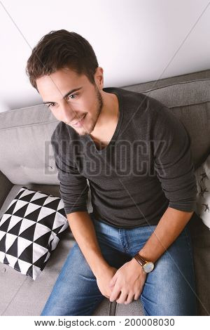 Attractive young man llying and relaxed on couch. Indoors.