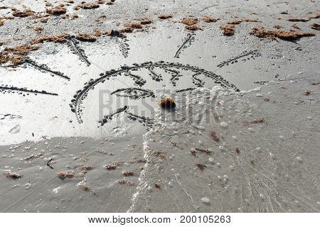The waves wash away the sun drawn on the sand. Farewell Summer!