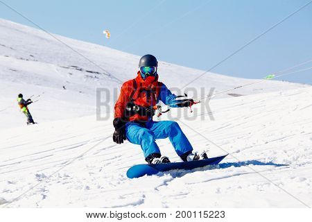 Snowboarder with a kite on fresh snow in the winter in the tundra of Russia against a clear blue sky. Teriberka, Kola Peninsula, Russia. Concept of winter sports snowkite.