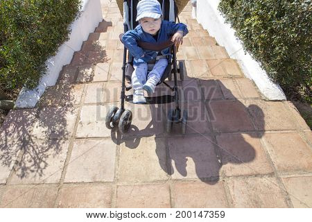 Mother carries a stroller down the stairs in garden without ramp for the disabled and baby prams