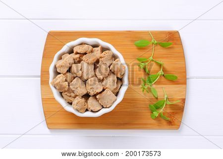 bowl of soy meat cubes on wooden cutting board