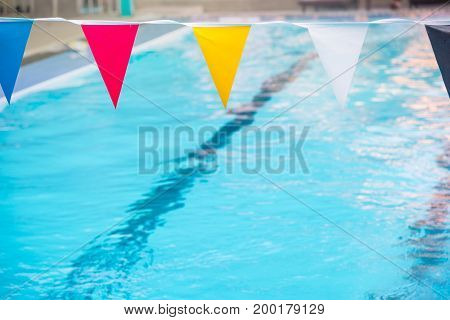 Close up of colorful flags over swimming pool with blurred of clear blue water background copy space.