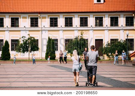 Grodno, Belarus - June 11, 2017: Young Family Couple With A Stroller Walking Near Old House Of Vice - Administrator In Sunny Summer Day In Hrodna, Belarus