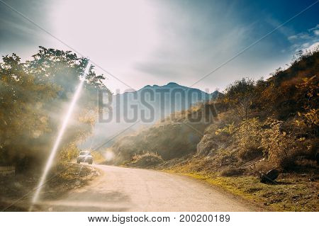 Khidistavi - Ateni - Boshuri Road, Patara Ateni, Shida Kartli Region, Georgia.  SUV Car On Country Road In On Autumn Sunny Landscape Background Of Georgian Mountains. Travel Concept