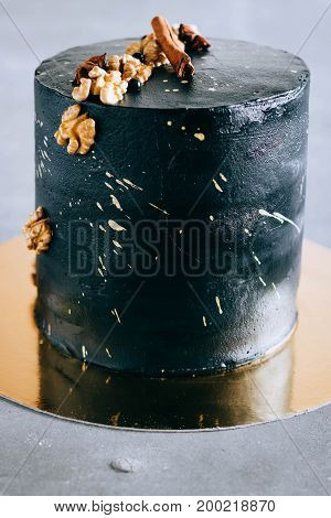 Black festive cake in space style with walnuts cinnamon and anise and golden spray