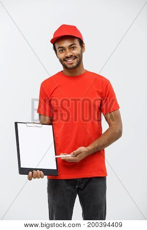 Delivery Concept - Portrait of Handsome African American delivery man or courier showing a confirmation document form to sign. Isolated on Grey studio Background. Copy Space.