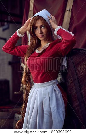 Townswoman in red dress with an apron and chaperone on the street. Costume stylized of later Middle Ages on 15/ 16th century.