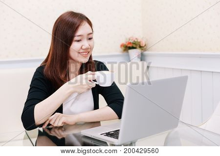 Happy Business Woman Holding Coffee Cup To Feel Good During Working Hours While Sitting At Her Worki