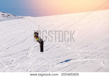 Snowboarder with a kite on fresh snow in the winter in the tundra of Russia against a clear blue sky. Teriberka, Kola Peninsula, Russia. Concept of winter sports snowkite.