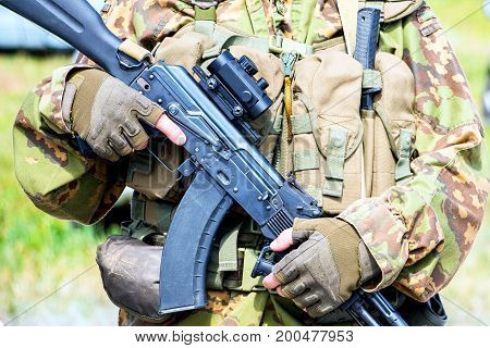 Soft focus. Soldier in camouflage holding a finger on the trigger of a Kalashnikov