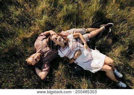 High angle view of first time parents resting on lawn and having fun. Top view of a smiling couple expecting their first child relaxing in the nature.