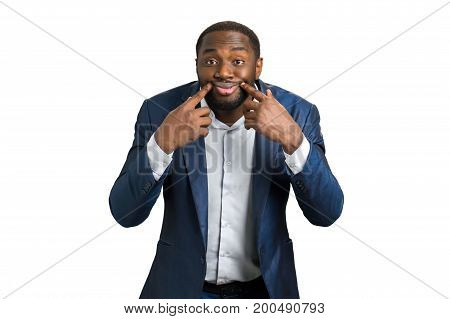 Young businessman making face. Portrait of businessman making a forced smile by his hands while standing isolated on white background.