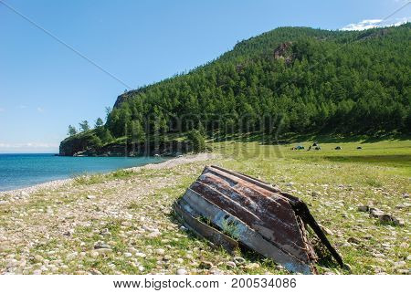 Old inverted fishing boat on the shore of a mountain lake