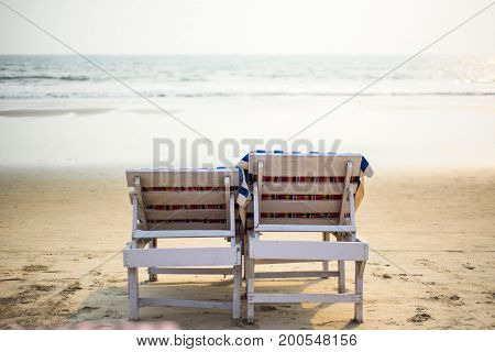 Two wooden deckchairs on a sunny beach