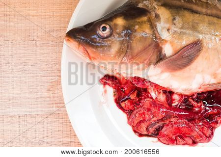 Gutted Carp Fish With Entrails On A White Plate.