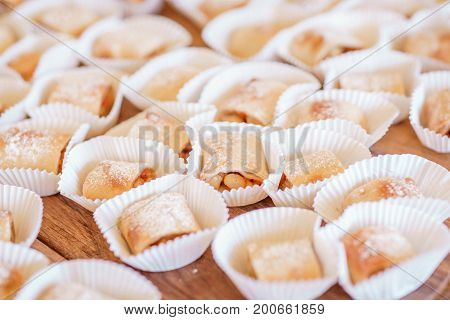 Set of  homemade fresh cookies dusted powdered sugar in white paper wrapper on wooden background.Sweet cookies with jam