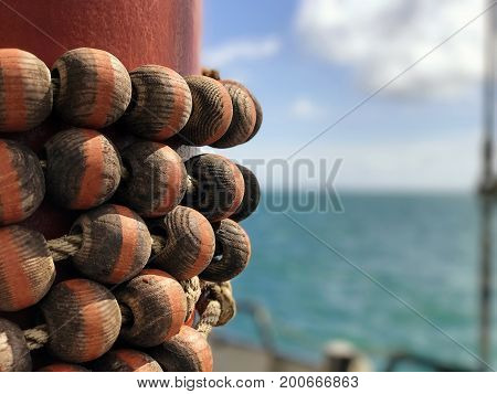Wooden Parrel Beads on a red mast of a yacht with a blurred background of the sea sky and horizon with space for text. Parrel beads are used to attach sail to mast to allow sail to slide up and down.