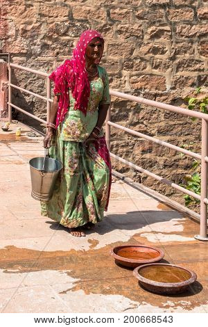 JODHPUR RAJASTHAN INDIA -MARCH 05 2016: Vertical picture of Indian woman carrying a bucket at Mehrangarh Fort in Jodhpur the blue city of Rajasthan in India.