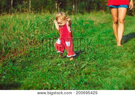 The child learns to walk in the park barefoot on the grass