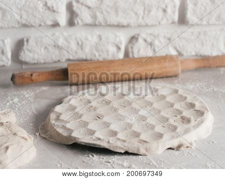 Process of making russian pelmeni, ravioli or dumplings with meat on white table. Homemade uncooked pelmeni and ingredients. Copy space