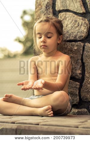 sad little cute girl sits on the pavement the concept of children