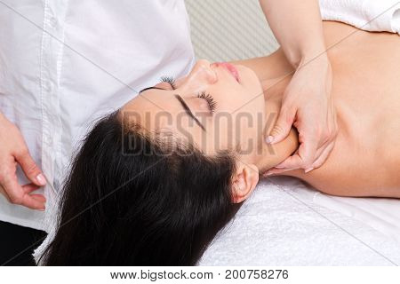 Neck massage in spa. Female beautician work in wellness center. Professional massagist make relax healthy procedure to beautiful indian girl in cosmetology cabinet or beauty parlor.