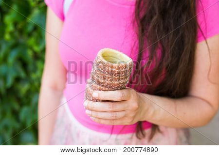 Close-up of young female tourist with traditional czech dessert trdelnik in Prague. Czech Republic. Outdoor.