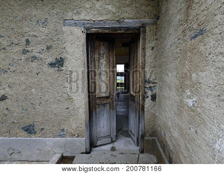 Weathered wooden door with a metallic rusty lock textured with white paint chipped and peeling