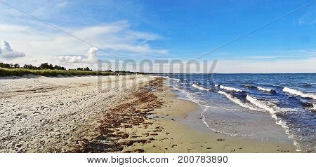 Beach in Marielyst denmark with ocean waves of baltic sea and blue sky - panorama view