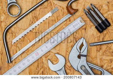 Tool concept pliers tine saw wrench on wooden plate and bird perspective.