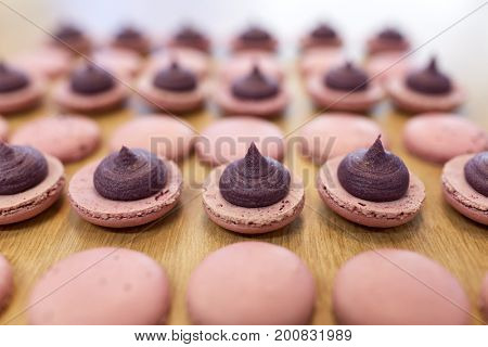 cooking, confectionery and baking concept - macarons with buttercream filling on table at bakery