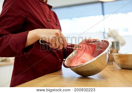 cooking, food and people concept - chef with spatula stirring macaron batter or cream in bowl at pastry shop kitchen