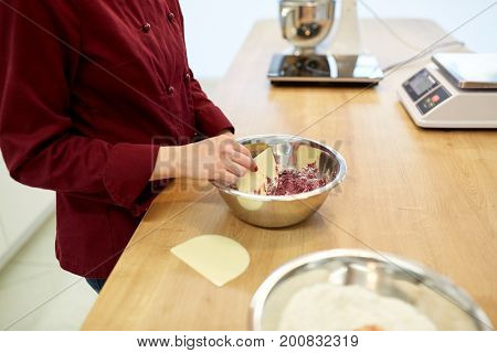 cooking, food and people concept - chef with spatula stirring macaron batter in bowl at pastry shop kitchen