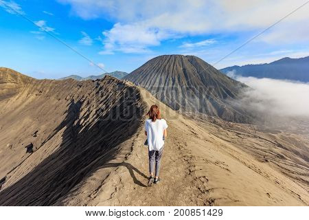 Female tourist walking through on the craters of Gunung Bromo and Sumeru volcanoes in Java Indonesia