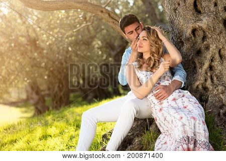 Loving young couple standing by trees at olive trees.