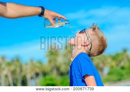 Portrait Of A Thirsty Handsome Boy In Sunglasses Drinking Water On The Desert Tropical Beach