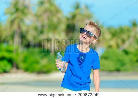 Portrait Of A Thirsty Handsome Boy In Sunglasses Drinking Water On The Desert Tropical Beach